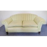 An early 20th century lime green upholstered 'shell-back' drop end sofa decorated with