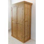 An early 20th century pine wardrobe: the outset cornice above two panelled doors enclosing hanging