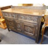 A reproduction oak sideboard: galleried back above two half-width drawers carved and incised with