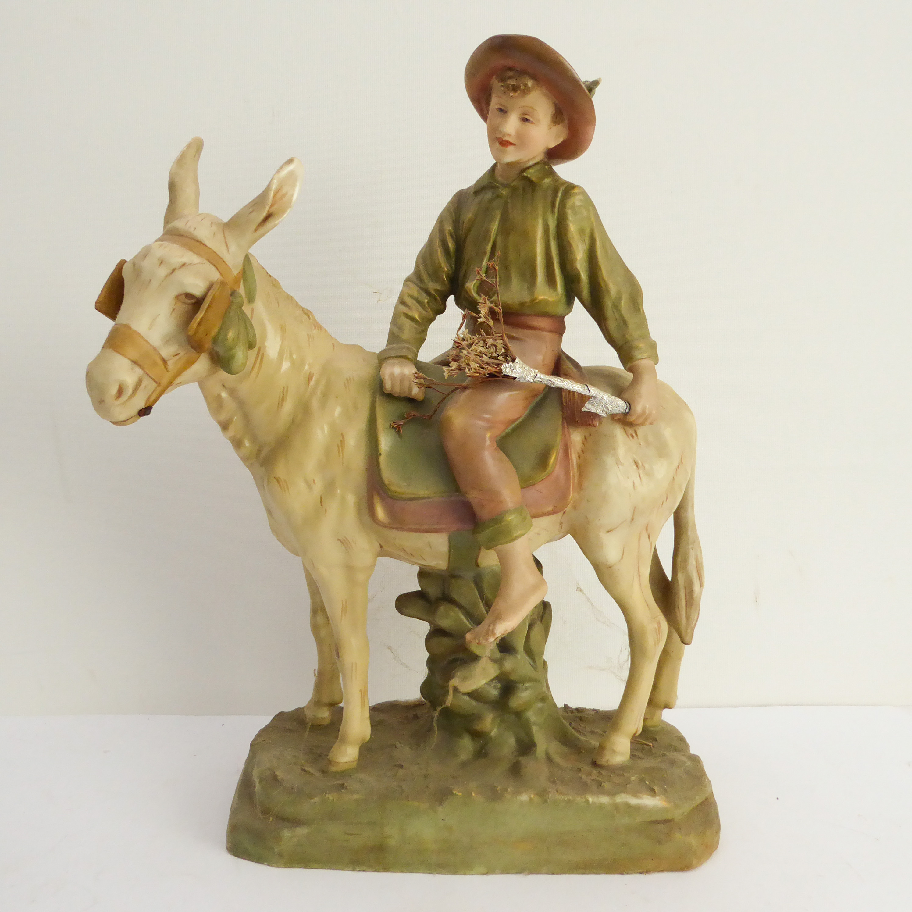 A large Royal Dux hand-decorated porcelain figure of a young boy in wide brimmed hat mounted upon