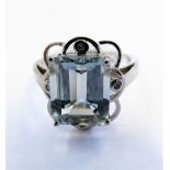 A 9 carat white gold ring set with a blue stone (possibly aquamarine) and four diamond chips, size