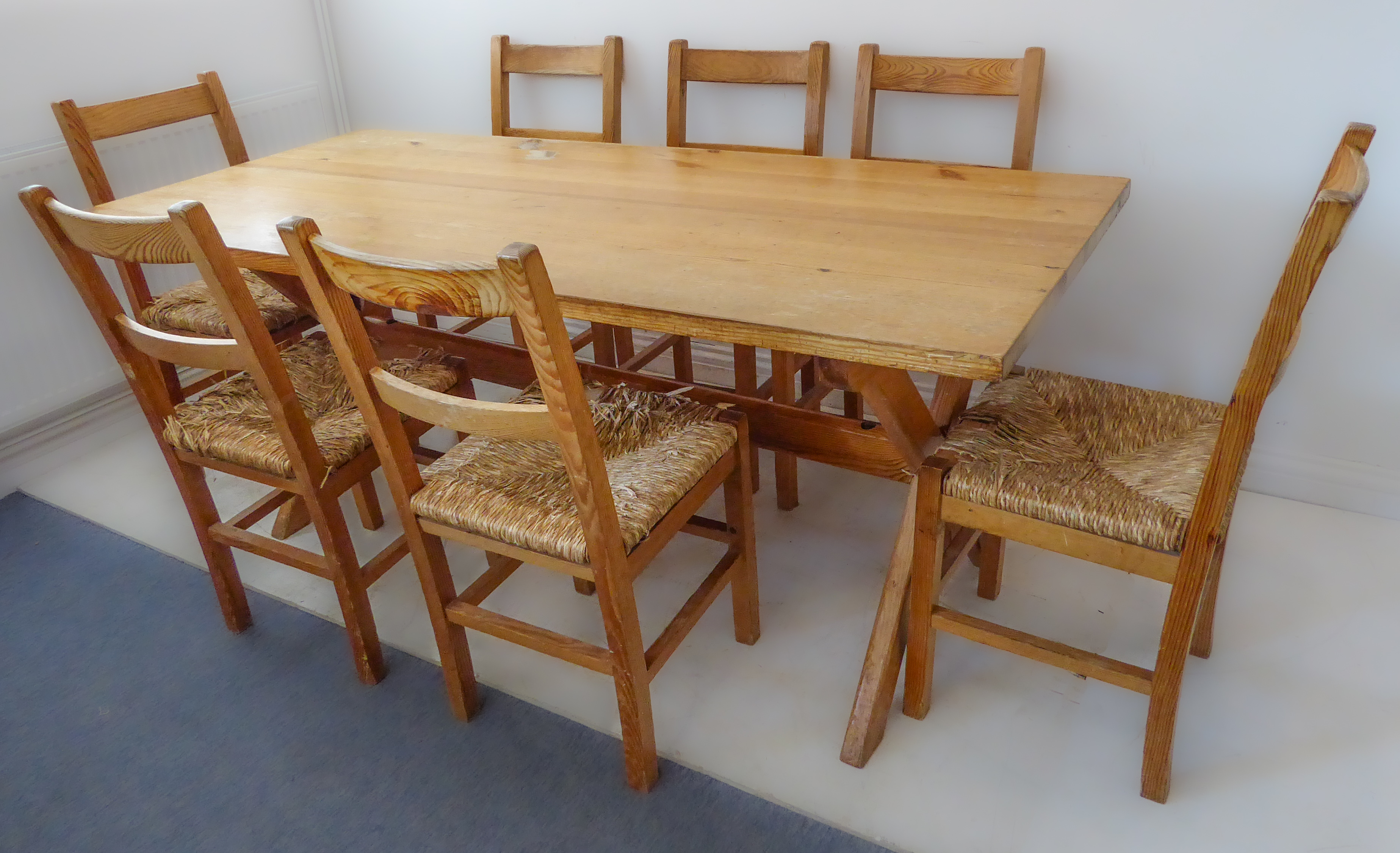 A pine kitchen-style planked top table upon cross form trestle style ends together with seven pine