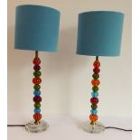 A pair of modernist multi coloured glass stemmed lamps: various and varying sized melon shapes above