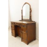 A mirror-topped oak dressing table in reproduction style: central drawer with arcading above two