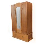 An Art Deco period bleached-oak wardrobe: central door with hand-bevelled mirror opening to reveal