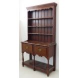 An early 20th century oak dresser of slim proportions and in George III style: the shelved