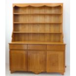 A large and modern light oak dresser; the shelved superstructure above the base with three flush