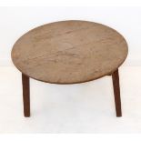 An oak cricket table; bleached circular top showing the medullary rays above three slightly splaying