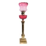 A 19th century brass and cranberry glass oil lamp: the crimped-top glass shade etched with flowers