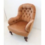 A 19th century light-brown Draylon upholstered button-back armchair raised on turned front legs with