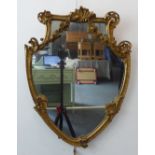 A late 19th/early 20th century gilt framed shield-shaped wall hanging looking glass (frame size 67cm