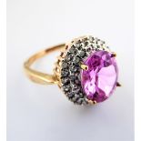 A 9 carat gold ring set with a central pink stone surrounded by white stones, size M/O