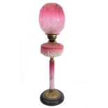 A 19th century brass, cranberry and opaline glass mounted oil lamp with ovoid cranberry-style