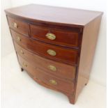 An early 19th century bow-fronted mahogany and strung chest; two half-width over three full-width