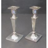 A pair of hallmarked silver table candlesticks of neoclassical inspiration: square tapering shafts