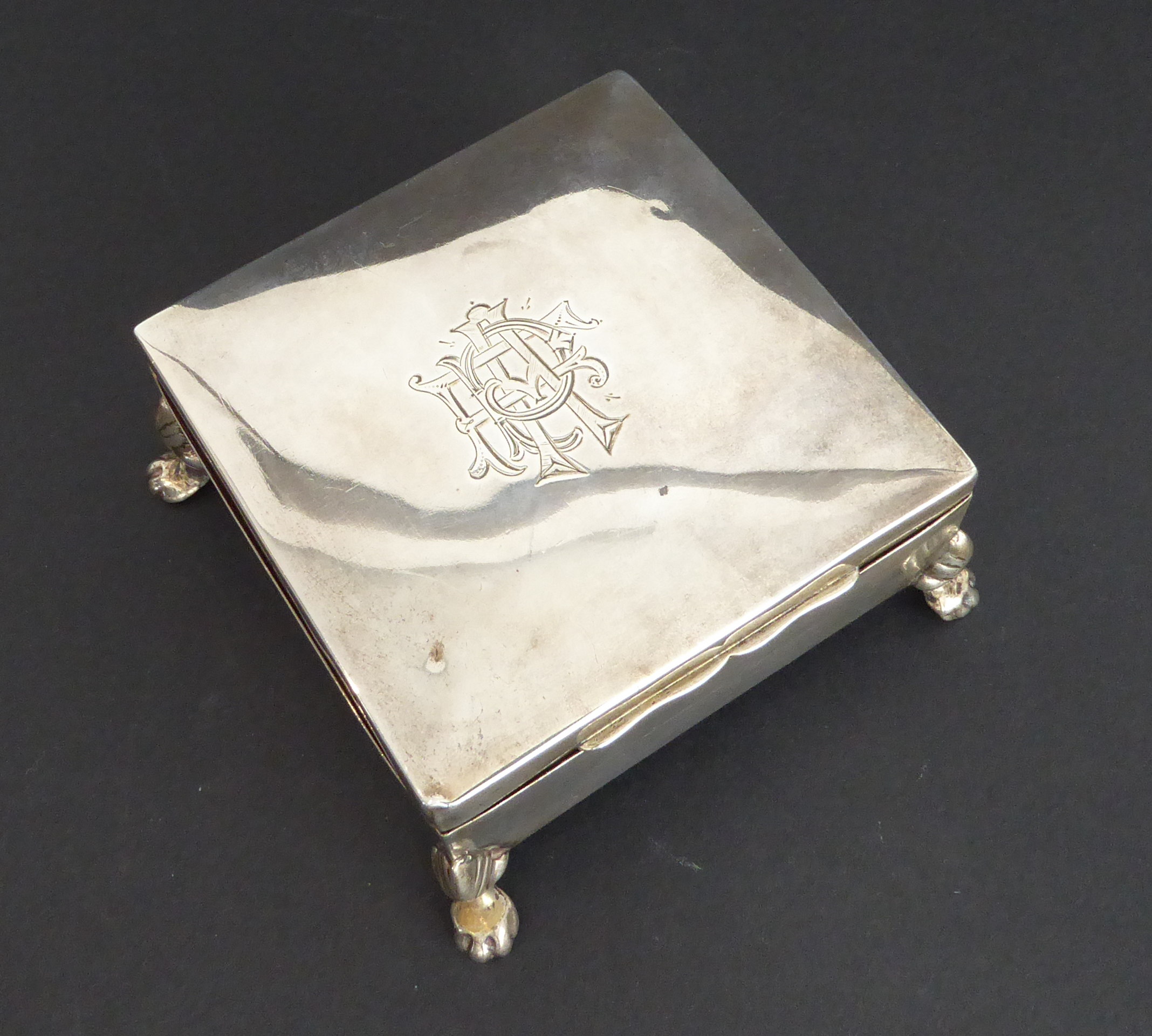 A hallmarked silver cedar-lined cigarette box: square form and raised on four animal's paw style