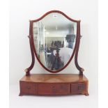An early 19th century bow-fronted mahogany and boxwood-strung toilet mirror: shield-shaped plate