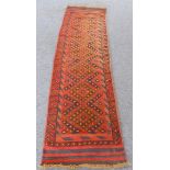 A modern Afghan runner rug of slim proportions: terracotta ground, lozenges and flat woven ends (