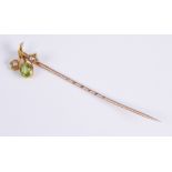 An antique 15ct gold, peridot and seed pearl stick pin: the flower shaped head set with an oval