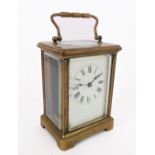 An early 20th century brass carriage clock timepiece: white-enamel dial with Roman numerals and with