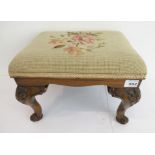 An early 20th century walnut footstool in 18th century style: the floral needlework top above a