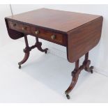A Regency period mahogany and rosewood crossbanded sofa table: the drop-flaps flanking two half-