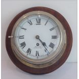 An early 20th century eight-day ship's bulkhead clock: mounted on a conforming circular mahogany