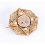 An Edwardian 14ct yellow gold, ruby and diamond plaque brooch: the flower shaped plaque centred by a