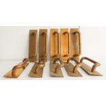 An unusual set of ten brass/bronze door pull handles: each handle against a vertical rectangular