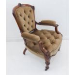 A fine walnut and buttonback upholstered open armchair: the top rail centrally carved and incised