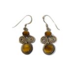 A pair of silver earrings: each of swirling design and set with a polished tiger's eye of oval