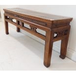 A 19th century Chinese elm low-table or bench: the top with cleated ends and sides; carved frieze