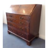 An 18th century walnut writing bureau: the crossbanded slanted fall opening to reveal a fitted