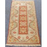 A small Turkish melas rug: central terracotta and cream rectangle flanked by cream borders with