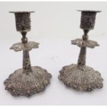 A pair of early 20th century Indian style white metal filigree table candlesticks: each pierced with