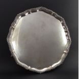A large and heavy hallmarked silver serving tray: gadrooned pie-crust style border raised on three