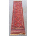 An Afghan runner of slim proportions: red ground with six lozenges and flatweave ends (231cm long