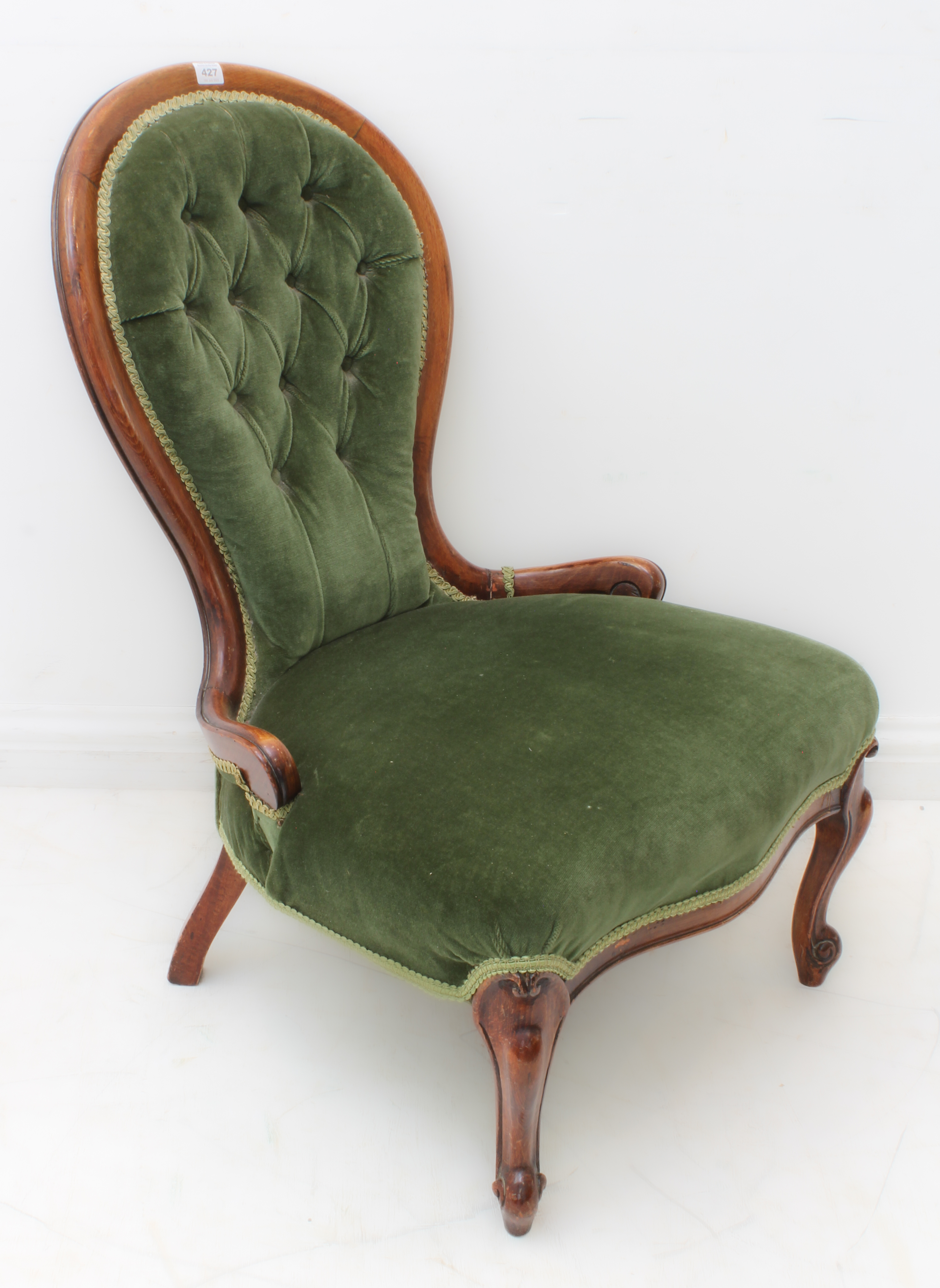 A 19th century buttonback upholstered nursing chair raised on moulded cabriole front legs.