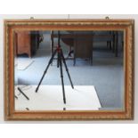 A rustic wall-hanging looking glass; the red ochre and gilded laurel-leaf style frame surrounding