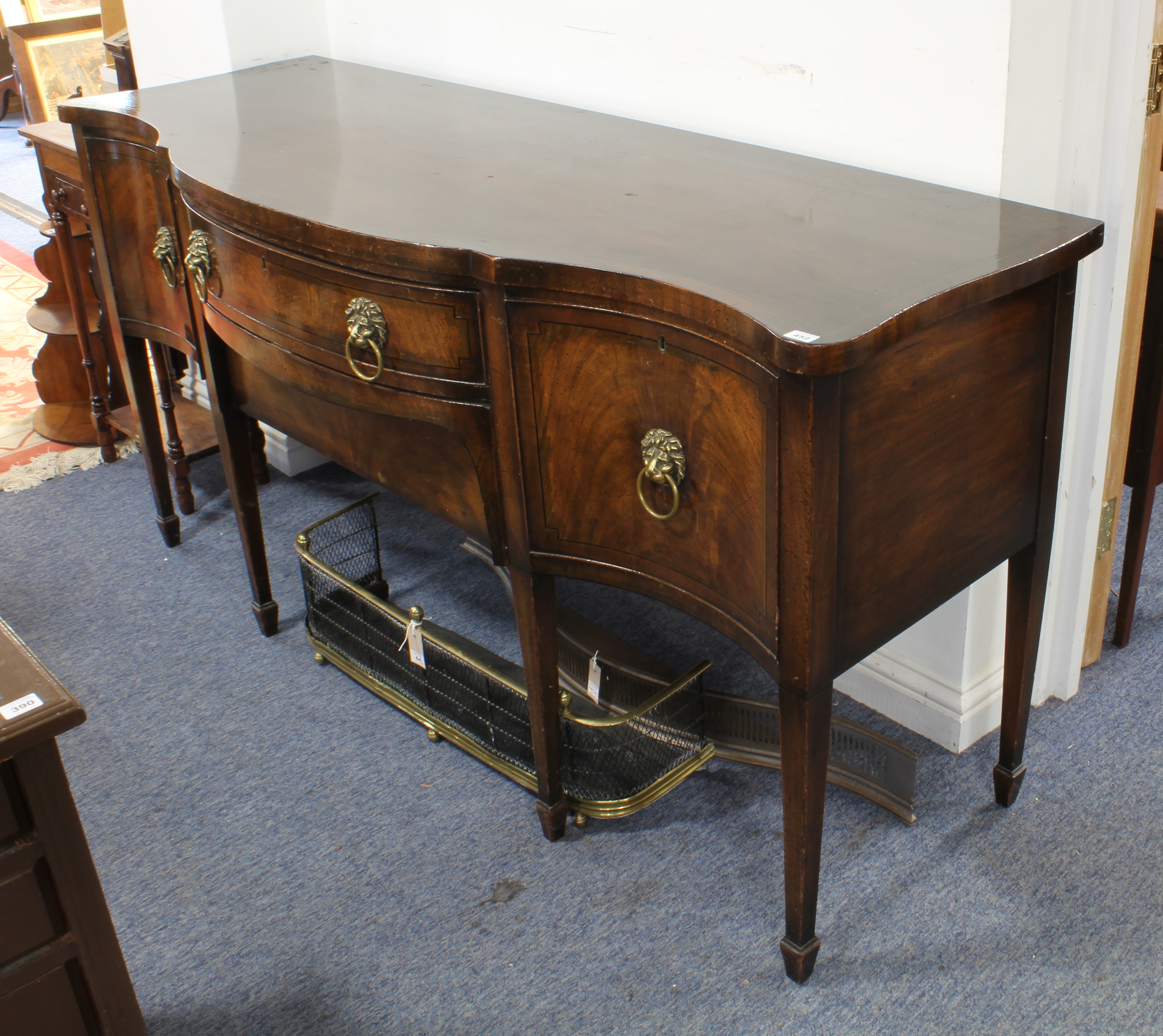 A serpentine-fronted mahogany and ebony-strung sideboard: central bow-fronted drawer above a slide-