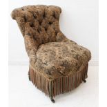 A late 19th century button-back upholstered nursing chair with tassels and ebonised front legs.