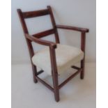 An early 19th century fruitwood open armchair: shaped arms, later overstuffed seat and on square