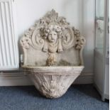 A stoneware water feature; cherubic mask spout above a bow-fronted attaching tray (55 wide x 75 cm