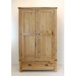 A modern solid oak wardrobe of large proportions; the slightly outset top above two panelled doors