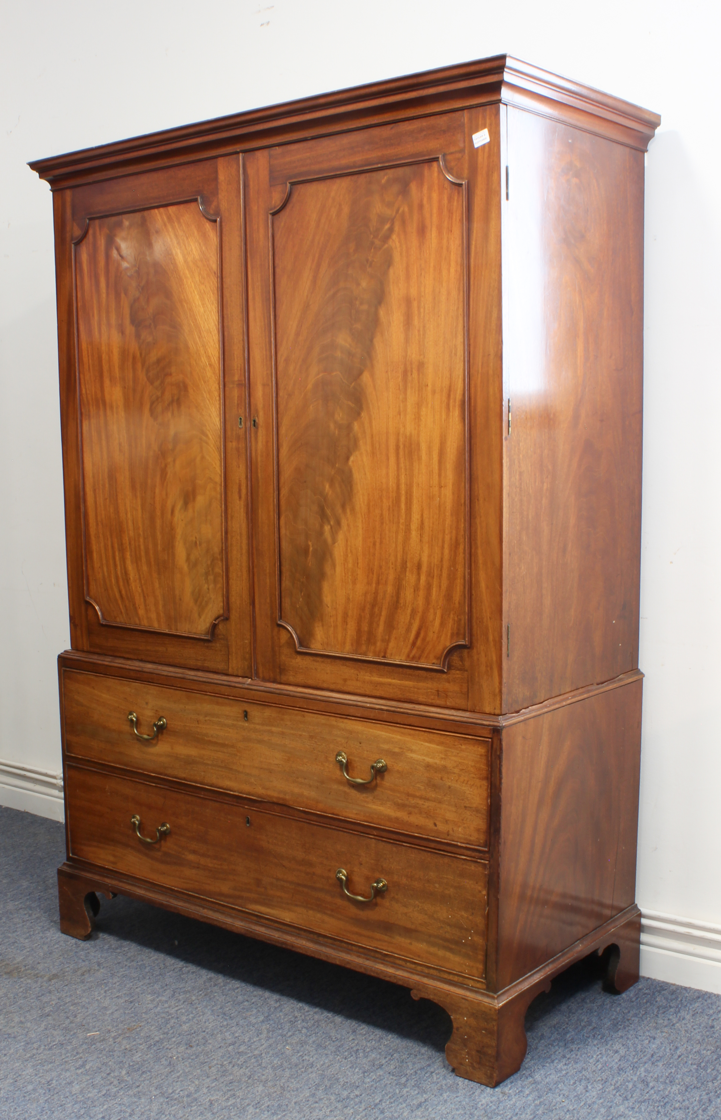 A late 18th century mahogany linen press: short outset cornice above two figured panel doors