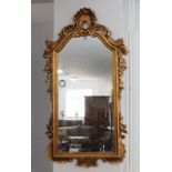 A modern reproduction wall-hanging looking glass in High Rococo style, pierced pediment with C-