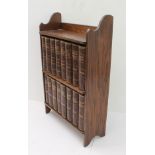 A set of 16  Charles Dickens volumes in their oak tabletop bookshelf (LWH 36 x14 x 56 cm). The early