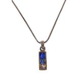 A silver pendant of vertical rectangular form: set with dark blue stone to the top, lighter blue and
