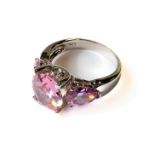 A silver dress ring mounted with a central oval light pink stone reflecting the light over the