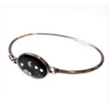 A silver bangle with hook style clasp: centrally set with a dark hardstone mounted with mother of